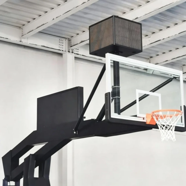 High-magnification detail of FIBA Level 1 portable basketball hoop showing 1800×1050mm 12mm clear view tempered glass backboard panel edge and full cover safety padding across base and front structure, illustrating glazing thickness and impact protection coverage