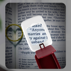 Close-up of the lamp's magnifying glass enlarging text on a book page.