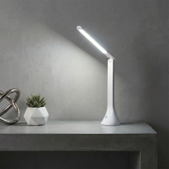 Portable COB folding LED desk lamp illuminating a modern workspace