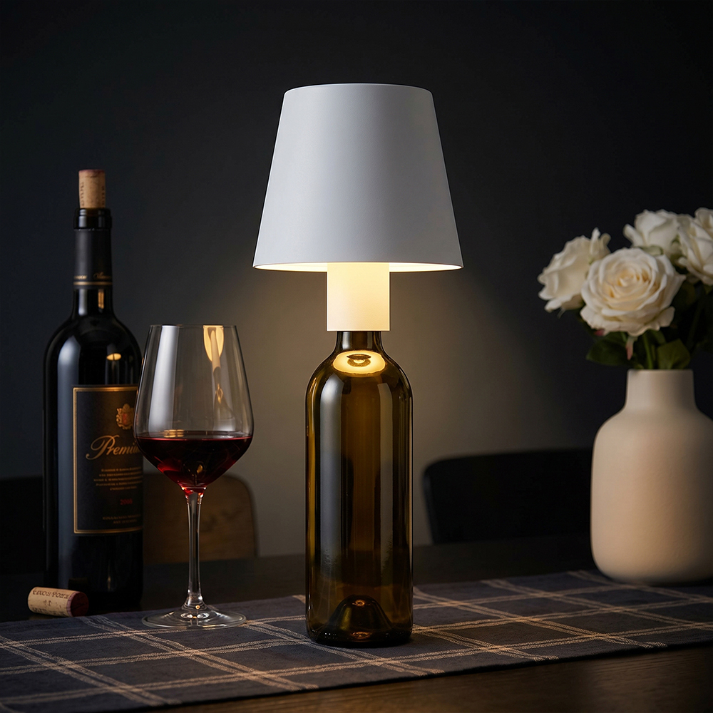 A creative white cordless LED desk lamp inserted into a wine bottle neck, illuminating a dining table next to a wine glass and white roses