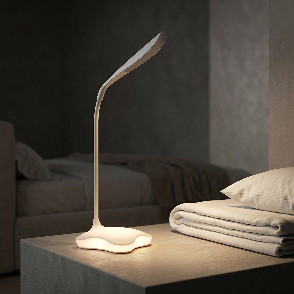 A sleek white LED bedside lamp with a glowing wave-shaped base lighting up a nightstand in a cozy bedroom setting