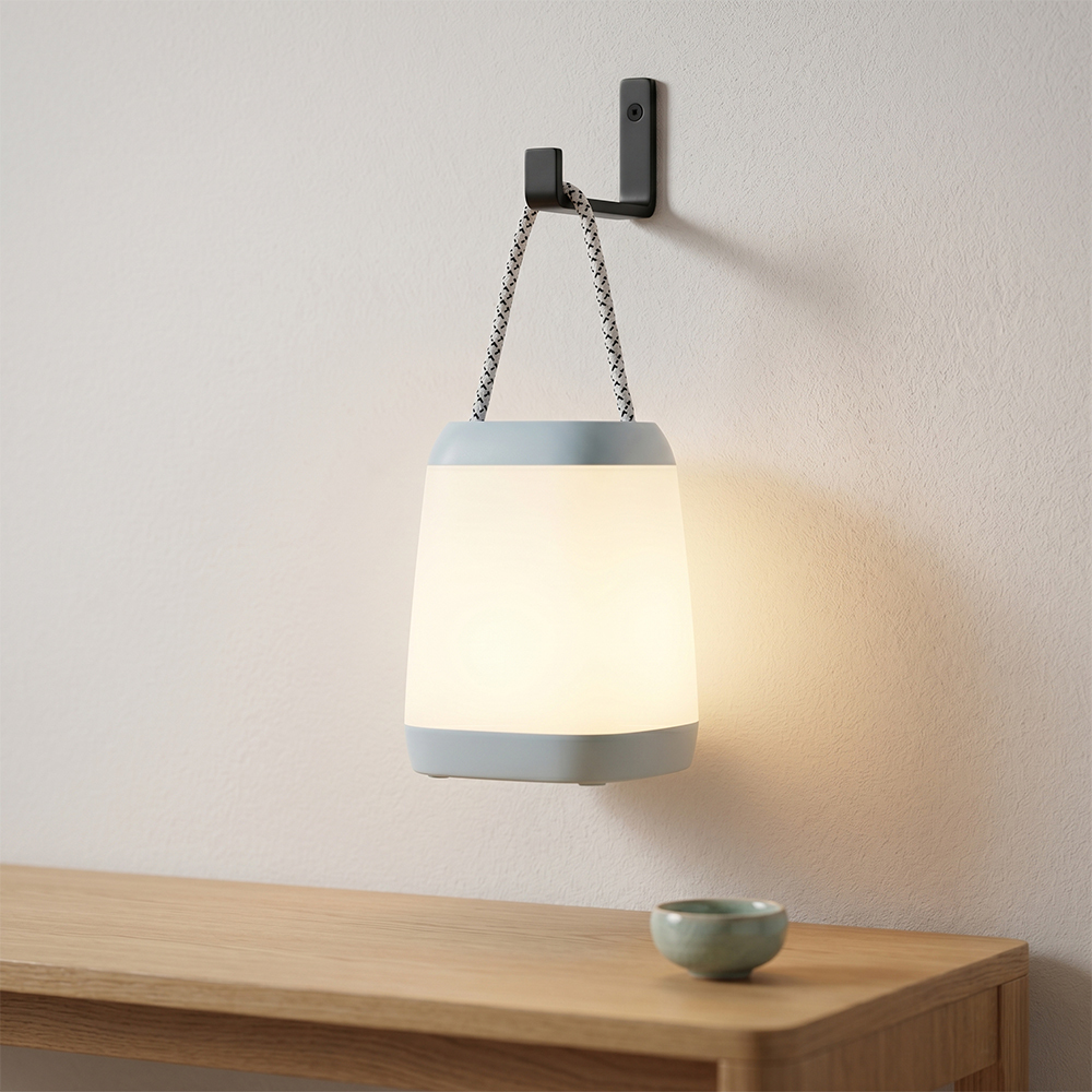 A cyan minimalist LED night light hanging from a black wall hook, casting a warm cozy glow over a wooden table