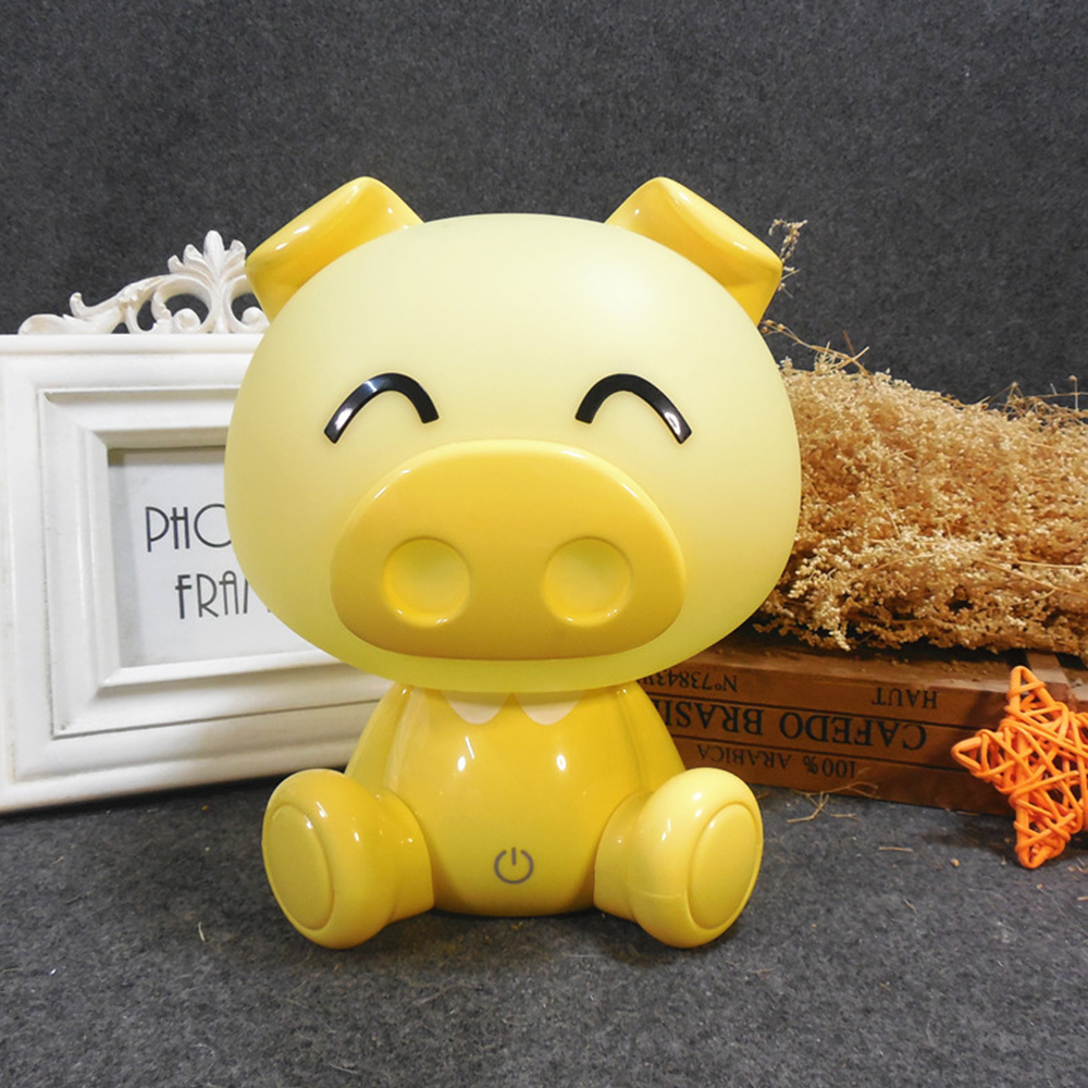 Front view of a cute light blue bear-shaped LED night light wearing glasses placed next to a photo frame