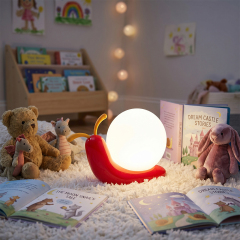 An illuminated snail night light glowing warmly on a white fluffy rug surrounded by storybooks, a teddy bear, and a plush bunny in a nursery