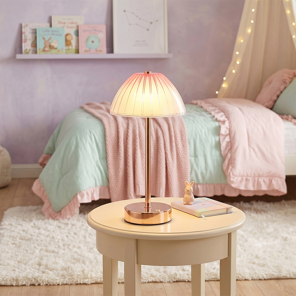 An illuminated cordless umbrella table lamp casting a soft warm glow on a small wooden table in a pastel pink and green bedroom layout