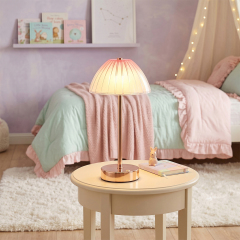 An illuminated cordless umbrella table lamp casting a soft warm glow on a small wooden table in a pastel pink and green bedroom layout