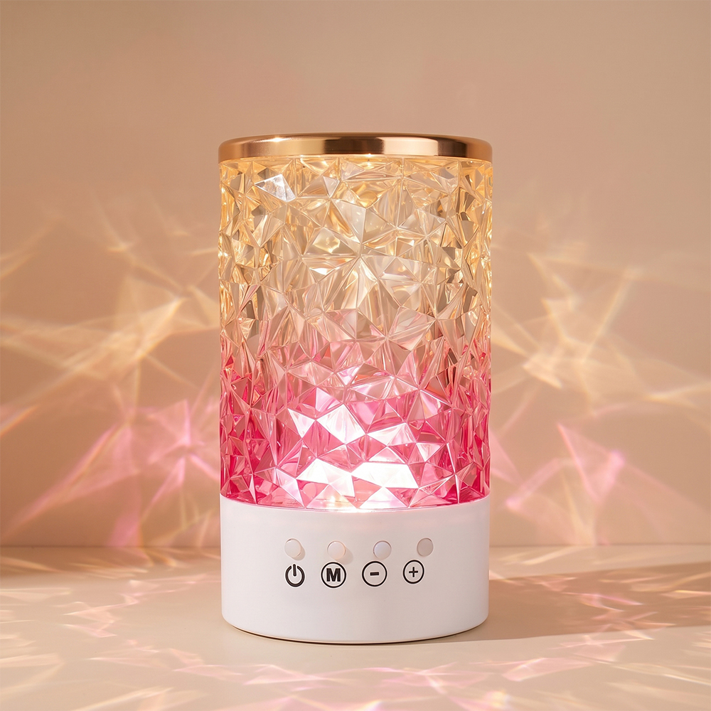 An illuminated crystal atmosphere lamp casting warm pink and orange geometric light patterns onto a wall background