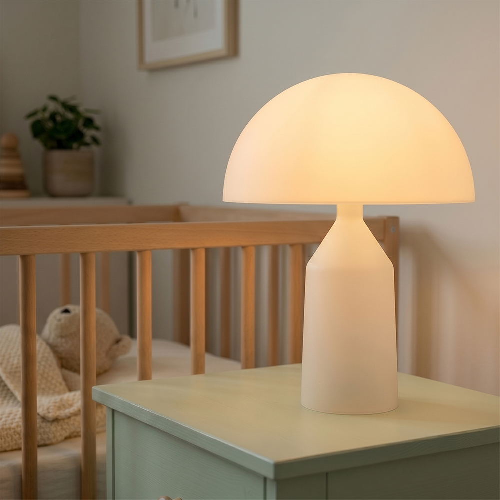 An illuminated white mushroom-shaped night light casting a soft warm glow on a bedside table next to a baby crib