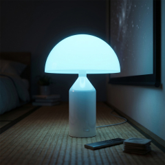A wireless mushroom table lamp glowing with a vibrant cyan light in a dark bedroom setting next to a smartphone