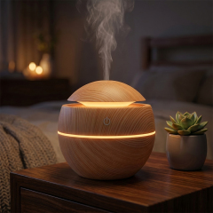A wood grain ball humidifier operating on a dark wooden nightstand, emitting a steady stream of mist and a warm glowing light band next to a small potted succulent in a cozy, softly lit bedroom.