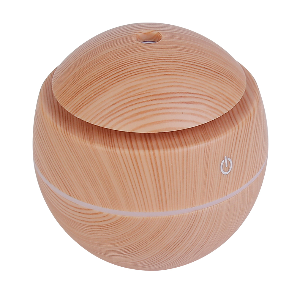 High-angle studio photograph of the assembled pinkish-brown wood grain round essential oil diffuser highlighting the top mist exit hole and front touch icon.