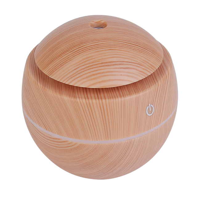 High-angle studio photograph of the assembled pinkish-brown wood grain round essential oil diffuser highlighting the top mist exit hole and front touch icon.