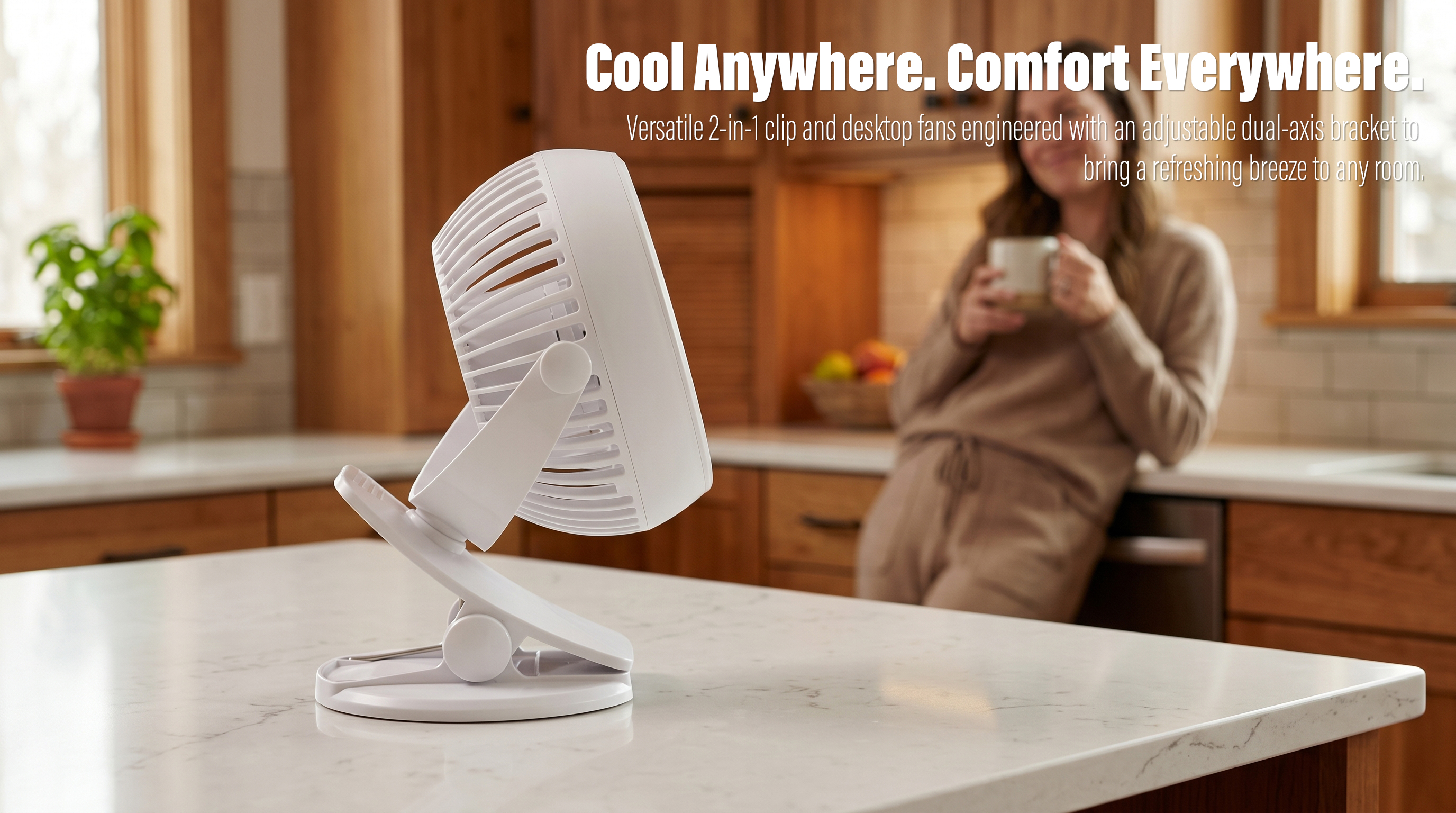 A white minimalist 2-in-1 clip-on desktop fan placed on a marble countertop in a modern kitchen with a woman holding a mug in the blurred background.