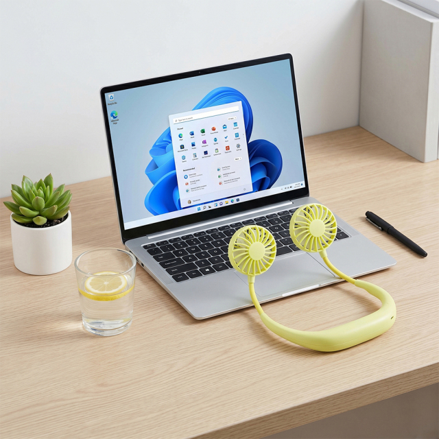 A pale green flexible neck fan folded and placed on a wooden office desk in front of an open laptop, for B2B sourcing.