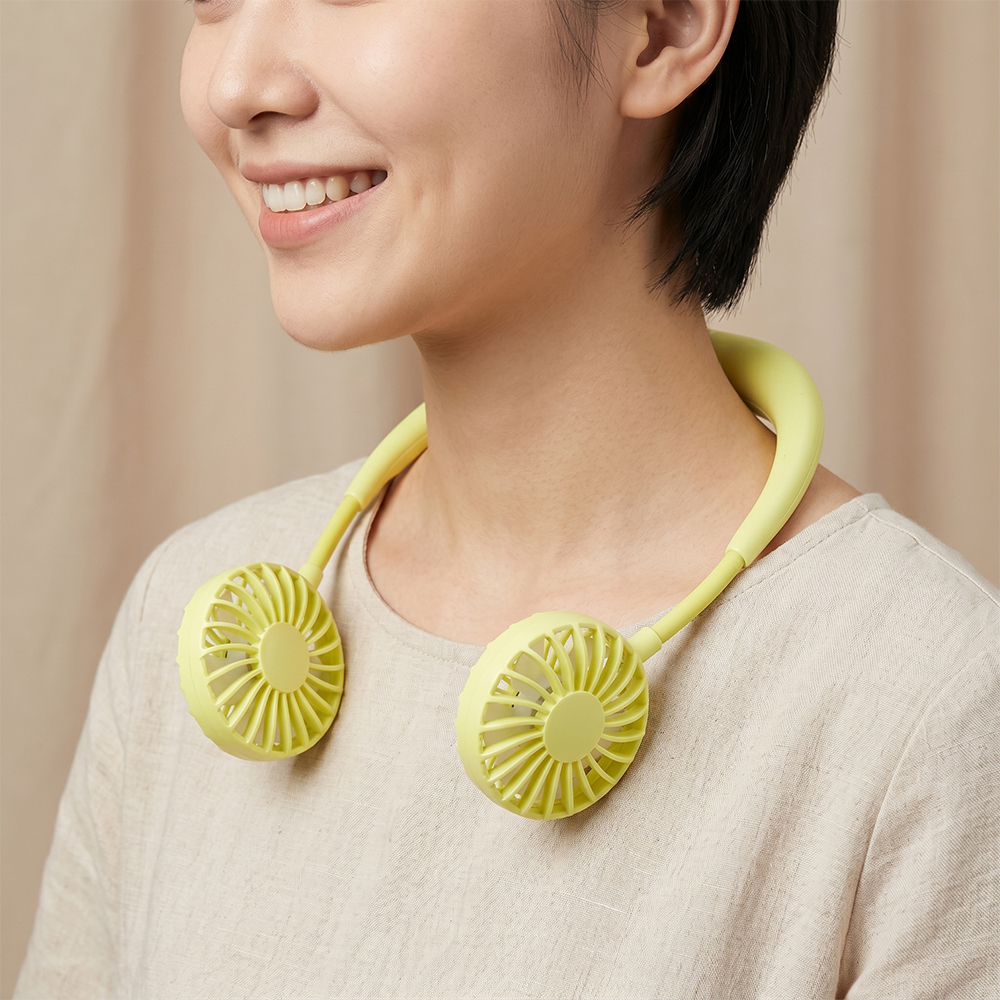 Close-up profile view of a smiling young woman wearing the pale green hands-free neck fan for personal cooling, for B2B sourcing.