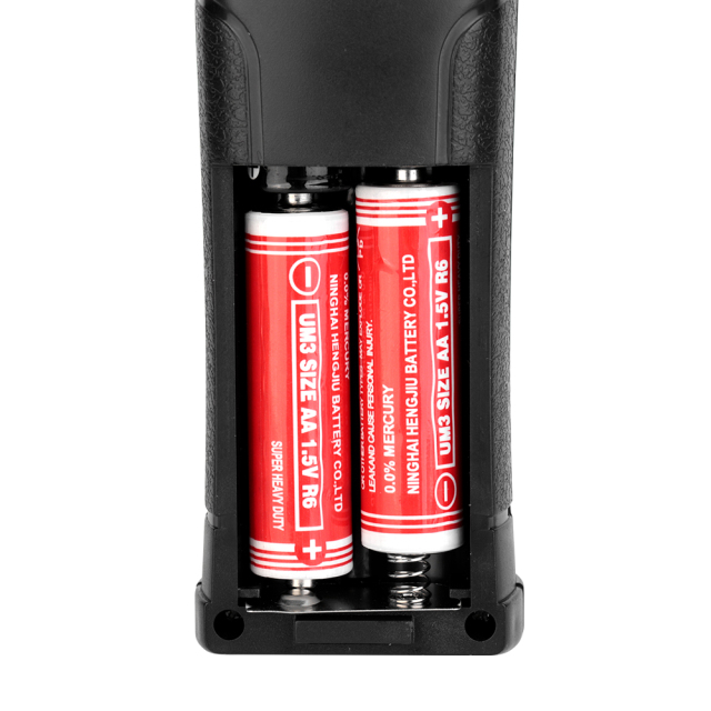 Close-up view of the open battery compartment on the back of the work light showing installed AA dry batteries.