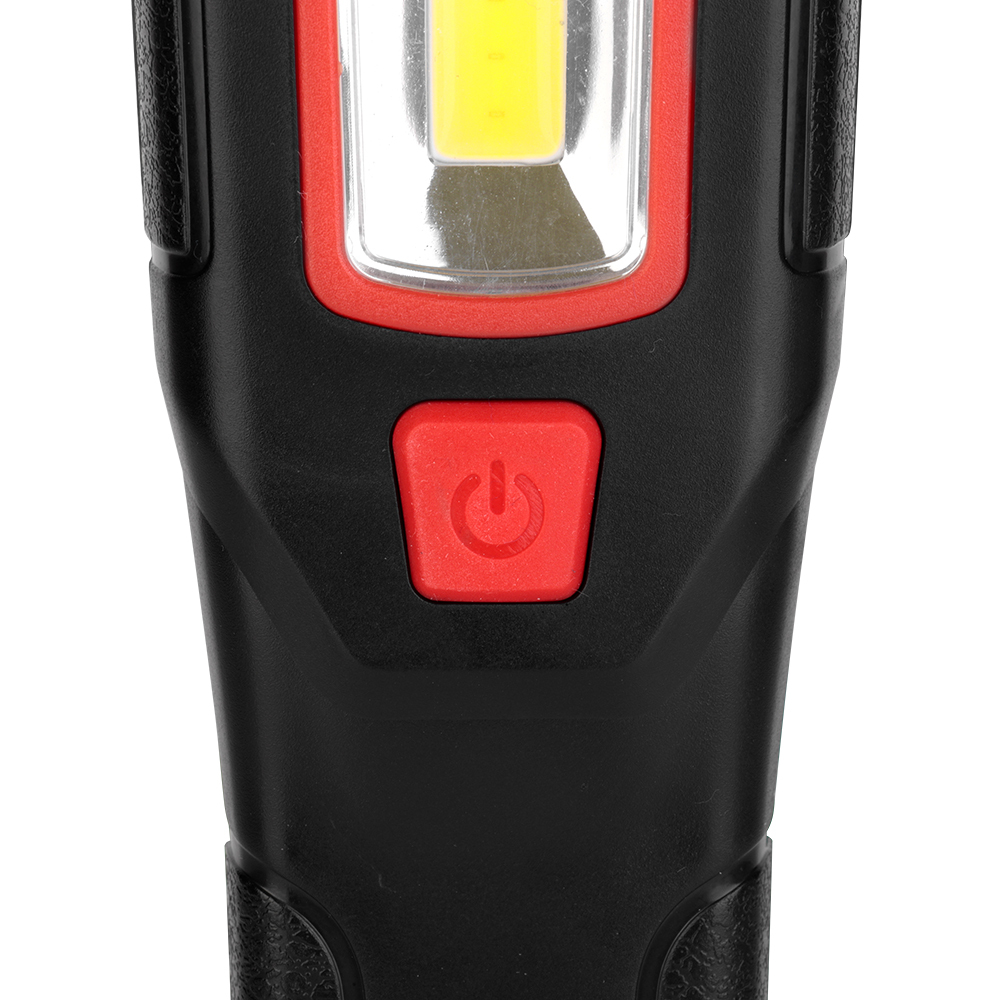 Close-up view of the textured red rubber power button on the front handle of the black work light.