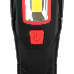 Close-up view of the textured red rubber power button on the front handle of the black work light.