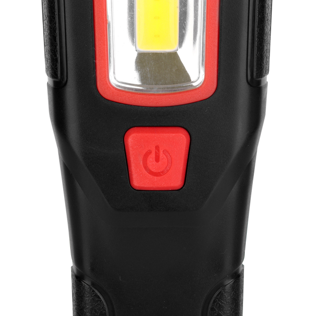 Close-up view of the textured red rubber power button on the front handle of the black work light.