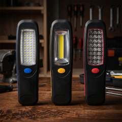 Three portable hands-free magnetic LED work lights with different LED array, COB panel, and dual-light configurations standing on a wooden workbench.