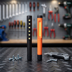 Two slim pen inspection lights—one black with 6LED SMD and one orange with COB—stand on a metal checker plate workbench.