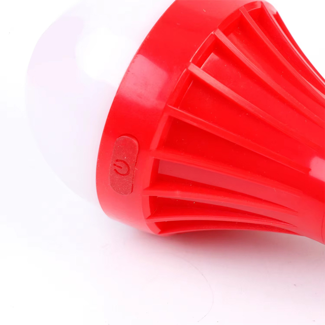 Close up view of the oval-shaped rubber power switch button integrated on the red plastic casing of the bulb light.