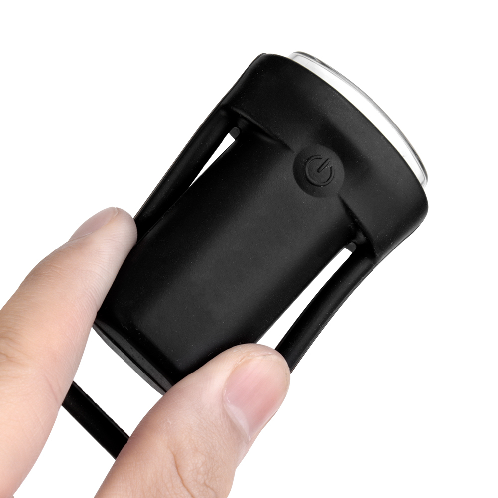 A person's hand holding the small black silicone bike light, demonstrating its mini lightweight size and stretchable mounting band.