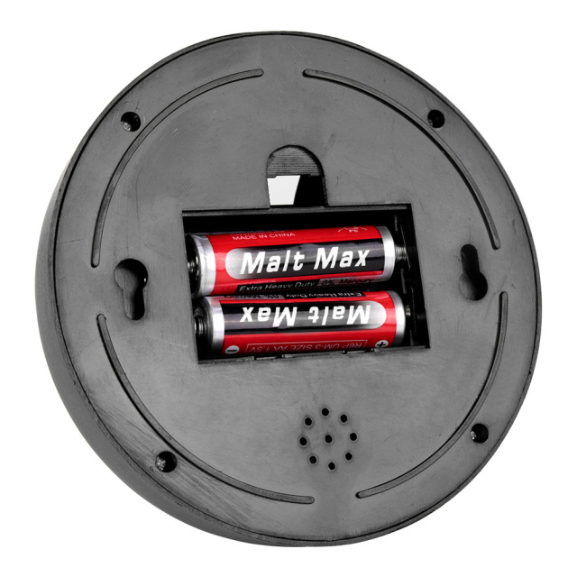 Rear view of the circular black camera base plate showing an open slot with two AA batteries inside, two wall-mounting slots, and a small round perforated hole pattern.