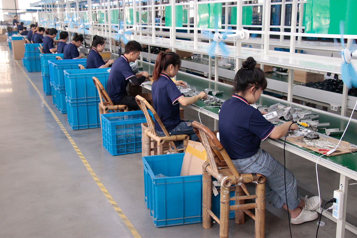 Professional electronics assembly line inside a 15,000 sqm portable lighting manufacturing facility, showing manual welding and mass production capability.