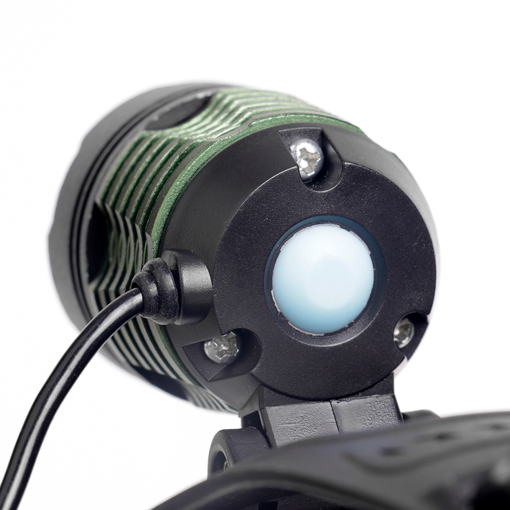 Close-up studio view from behind the lamp head, showing the green anodized aluminum heat-dissipating cooling fins and the central light blue rubber push-button switch.