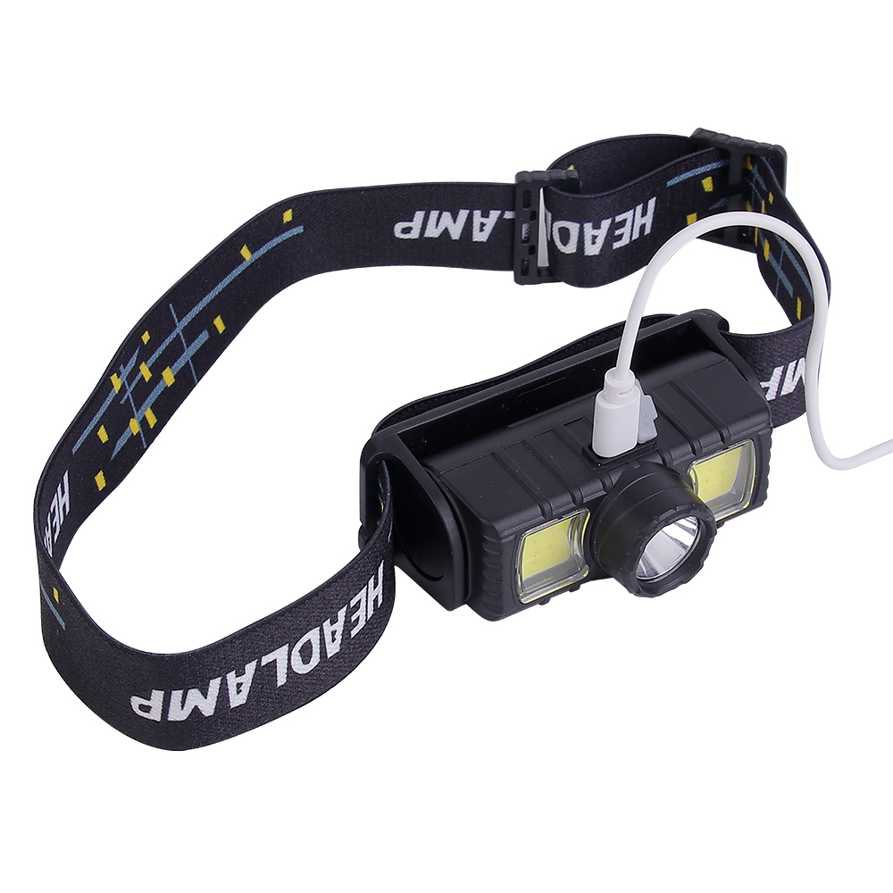 Studio top-angle view of the compact head torch with a white Micro USB charging cable connected directly into the top power port of the housing.