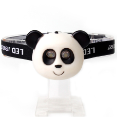 Studio front view of a white and black custom cartoon panda-shaped kids LED head torch displayed on a clear stand.