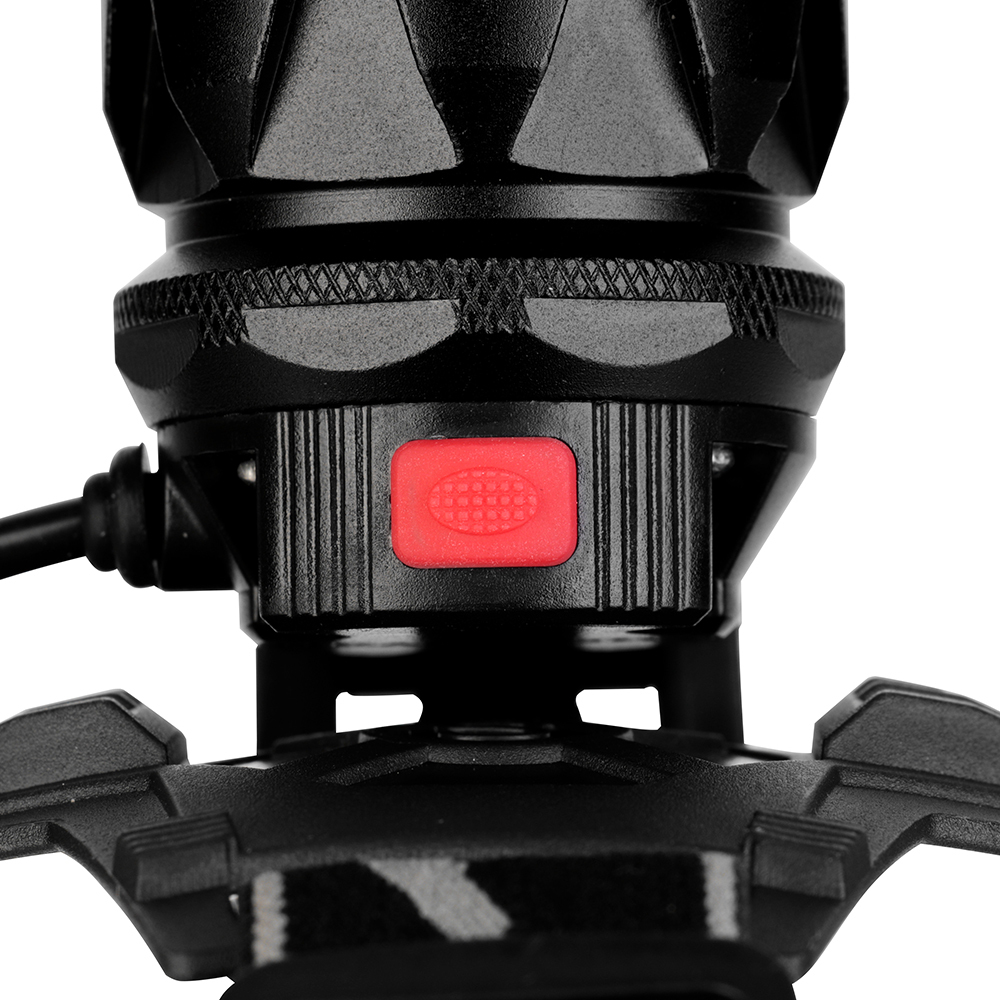 Studio close-up view from above the lamp head, focusing on the rectangular textured red rubber push-button power switch integrated into the top of the black aluminum housing.