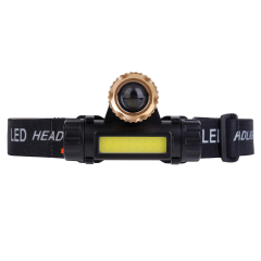 Studio front view of the zoom variant headlamp, featuring a prominent golden anodized aluminum rotating zoom bezel sitting above the horizontal yellow COB panel.