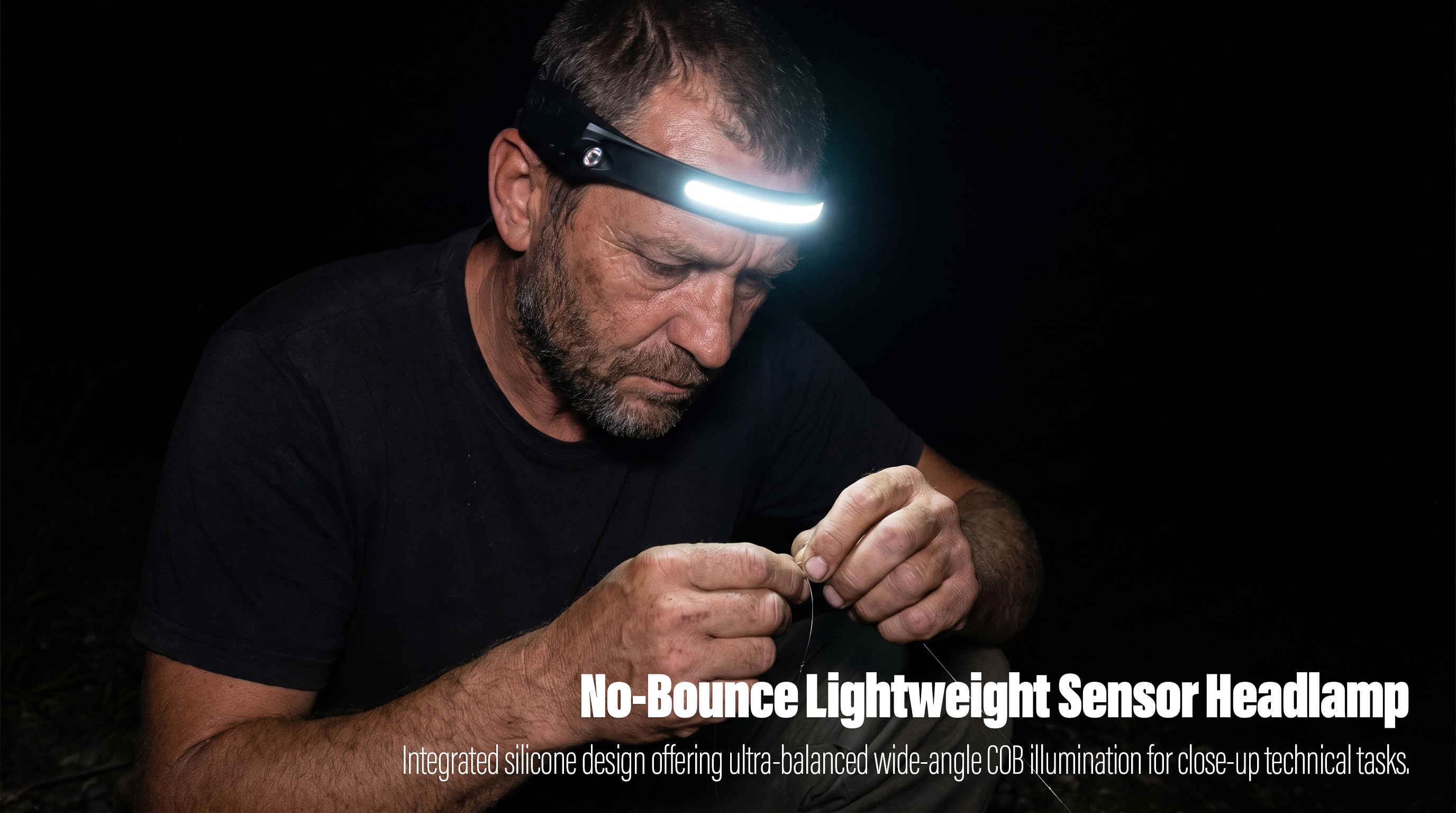 A real-world outdoor night photo of a man wearing a sleek black silicone strip headlamp, with its integrated front COB LED band illuminating brightly to cast a direct white light onto his hands as he precisely ties a thin line.