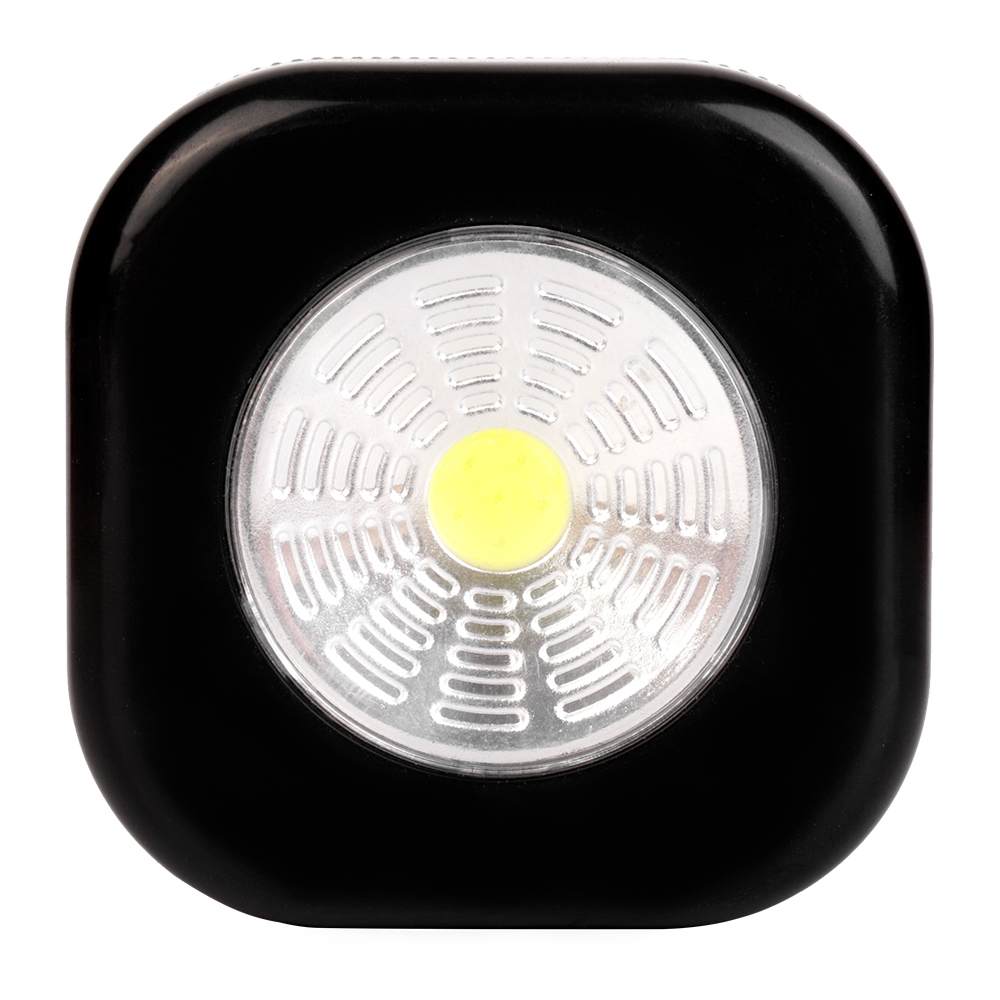 Studio front view of a black rounded-square wireless puck light featuring a large circular COB LED panel with a yellow center.