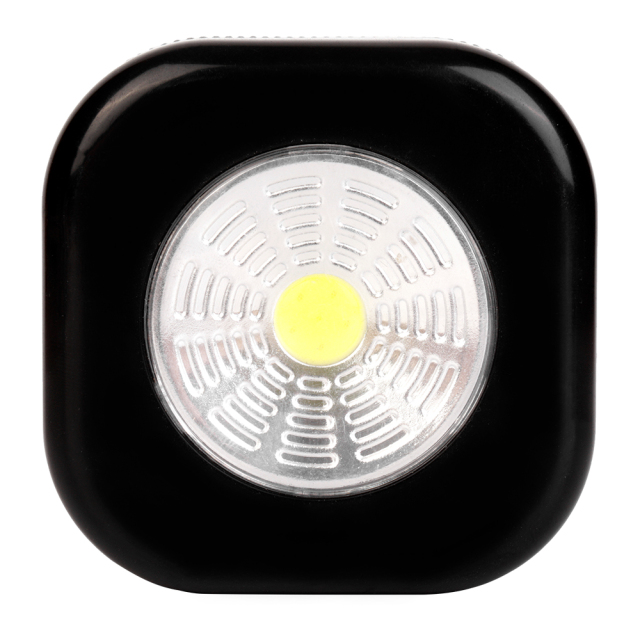 Studio front view of a black rounded-square wireless puck light featuring a large circular COB LED panel with a yellow center.