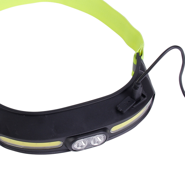 Studio top-down view of the headlamp casing, showing a black cable plugged into the built-in Type-C charging port with its protective rubber flap flipped back.