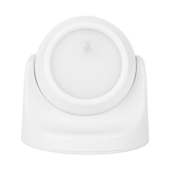 Studio front view of a white spherical wireless motion sensor light inside its curved mounting base, with the circular lens facing forward.