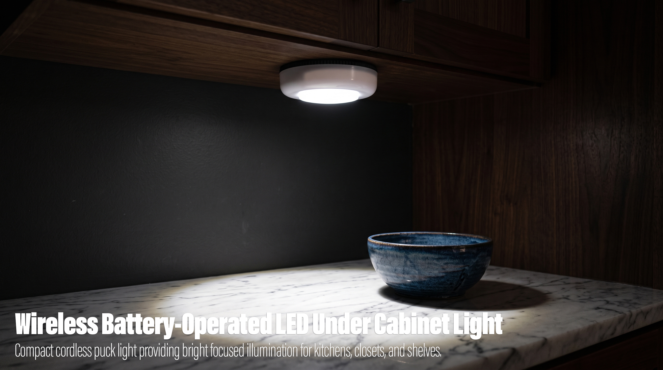 A round white battery-operated LED puck light mounted under a wooden kitchen cabinet, casting a bright pool of light onto a marble countertop and a blue ceramic bowl.