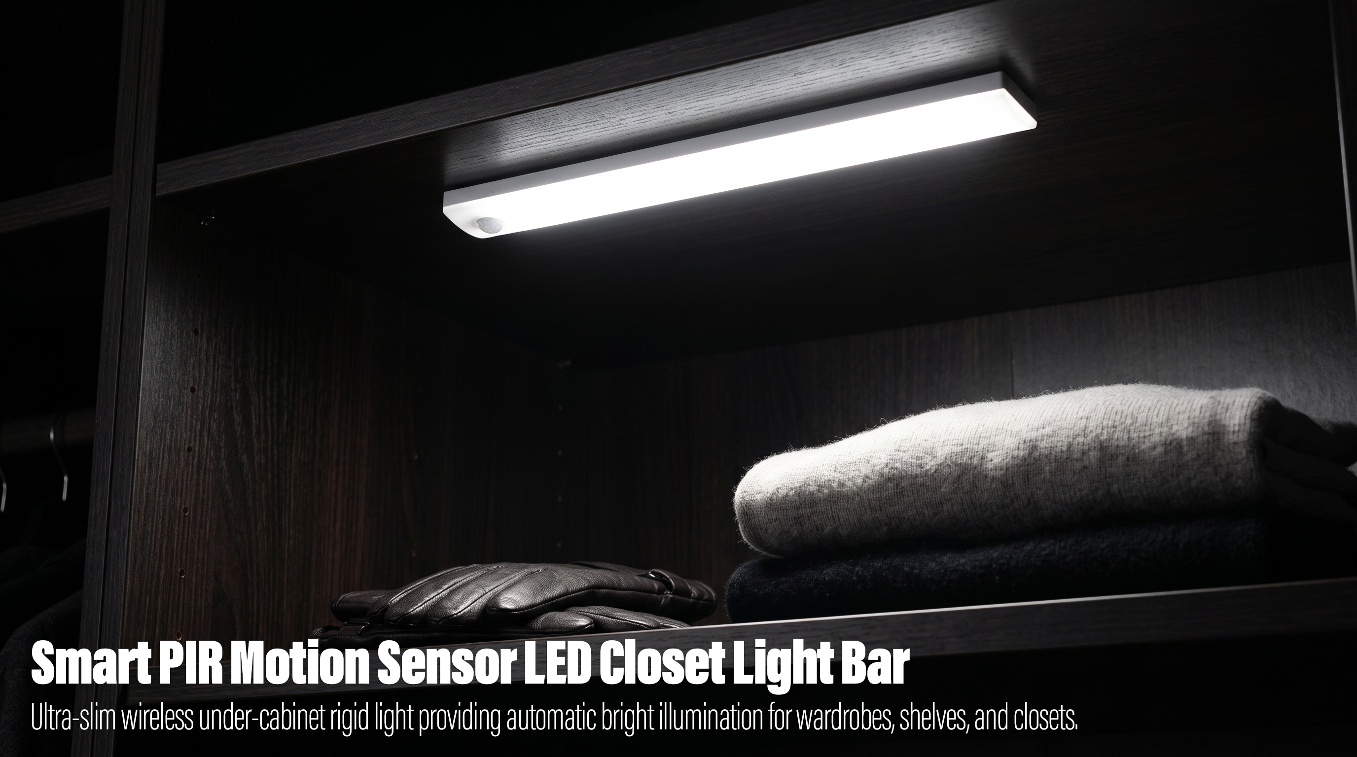 A slim white wireless PIR motion sensor LED light bar mounted under a dark wooden shelf inside a closet, casting bright light onto folded sweaters and a pair of leather gloves.
