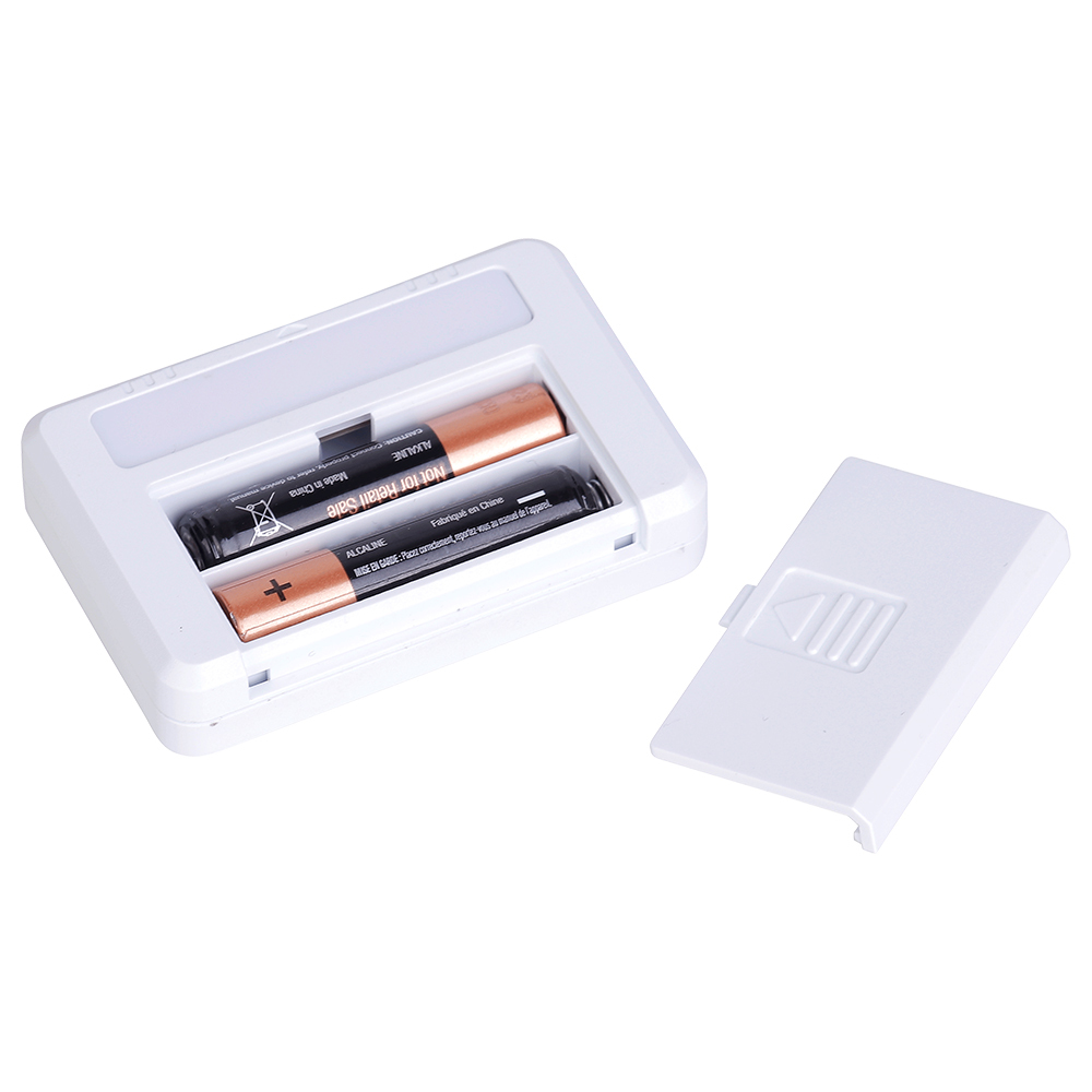 An open battery compartment of the white drawer light showing two AAA batteries installed inside alongside the removed cover.