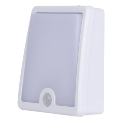Studio three-quarter angle view of the white freestanding LED night light, displaying its wedge-shaped housing design that allows it to stand independently.
