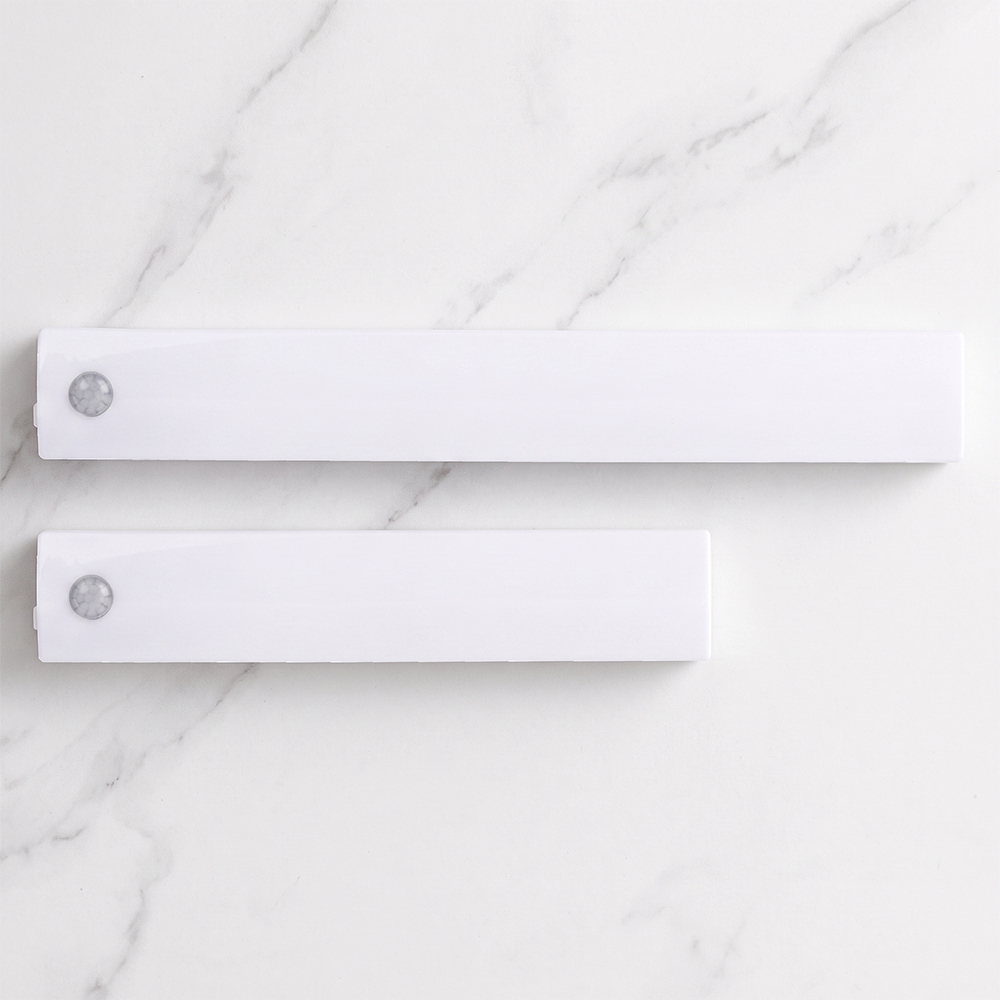 Top view of two different sizes of white wireless PIR motion sensor LED closet light bars placed on a white marble background.