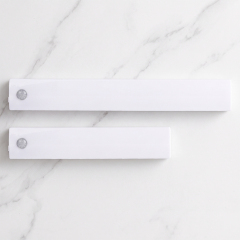 Top view of two different sizes of white wireless PIR motion sensor LED closet light bars placed on a white marble background.