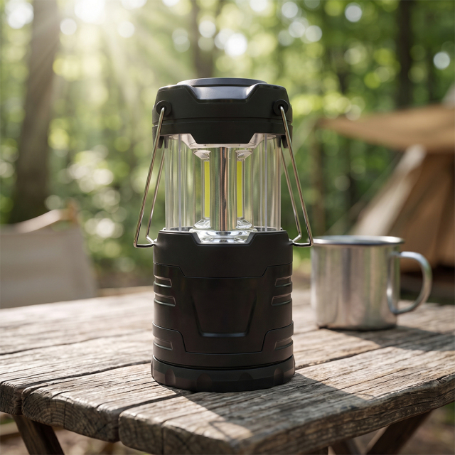 A fully expanded black collapsible LED camping lantern with metal handles on a rustic wooden table in a forest setting.