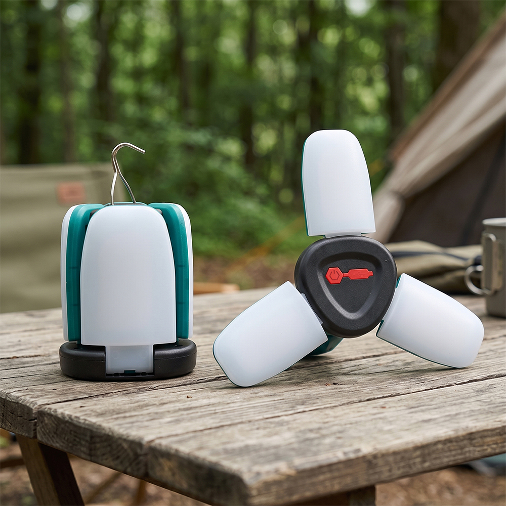 Two collapsible LED camping lanterns on an outdoor wooden table, showing one in a closed cylinder shape and the other with three light panels fully expanded.