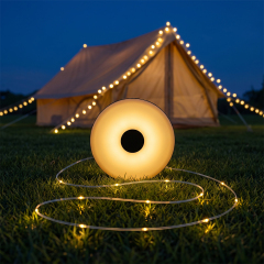 A glowing round warm-light camping lantern on the green grass with its extended 10m LED string light illuminating a luxury tent at night.