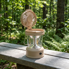 A light brown rechargeable camping lantern with its top cooling fan flipped open, sitting on a weathered grey wooden park bench with a green forest background.