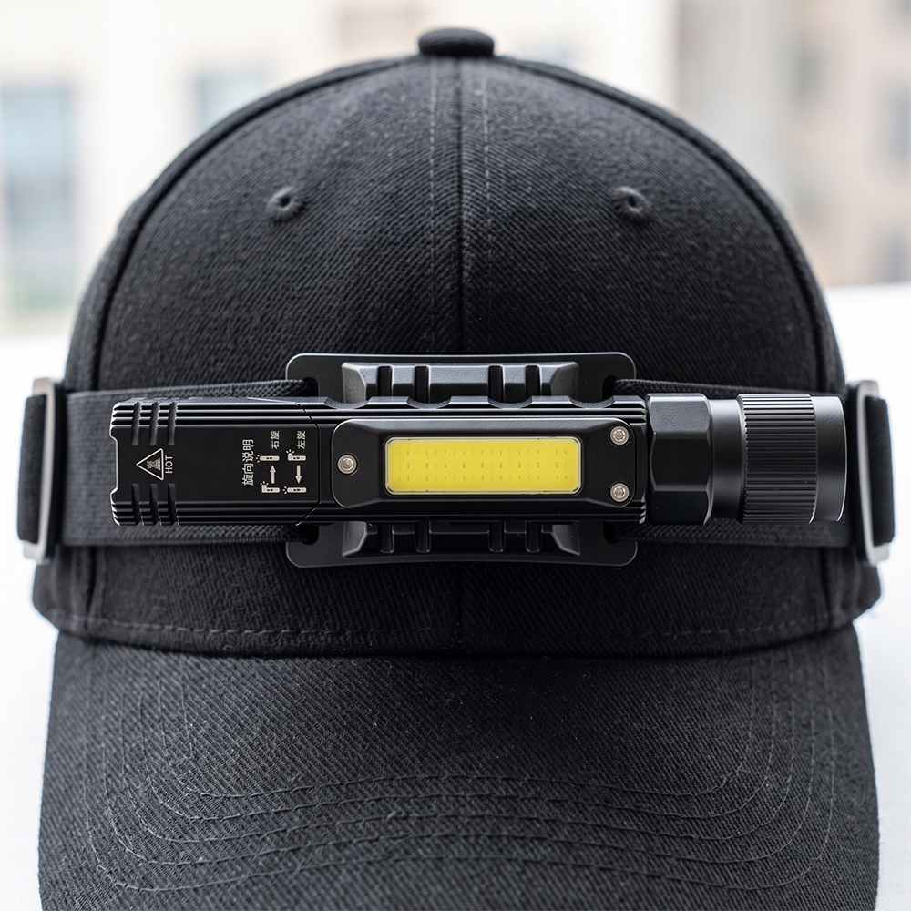 The compact right-angle flashlight mounted on an adjustable headlamp strap and worn over a black baseball cap.